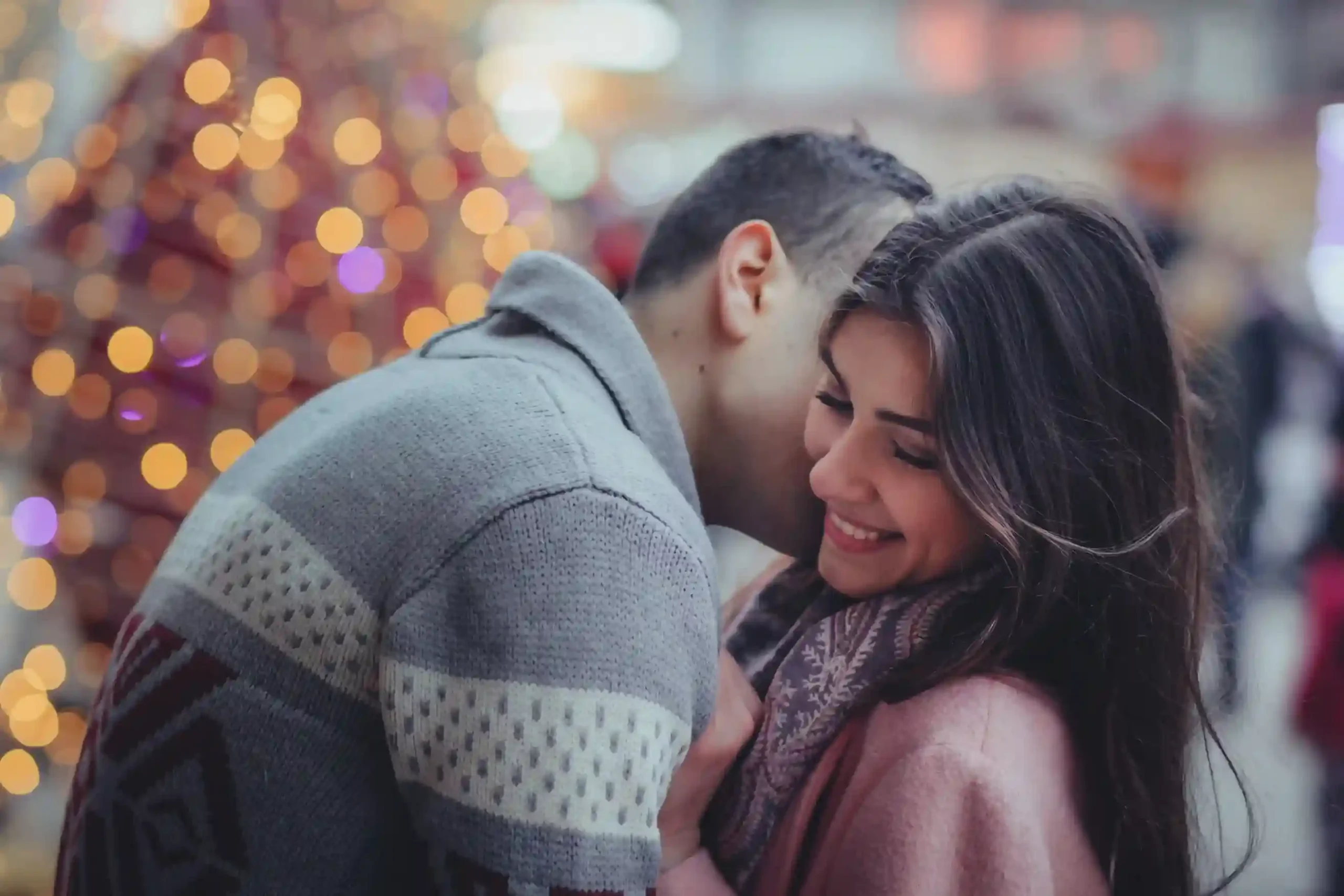 Un couple partageant un moment de tendresse devant des lumières